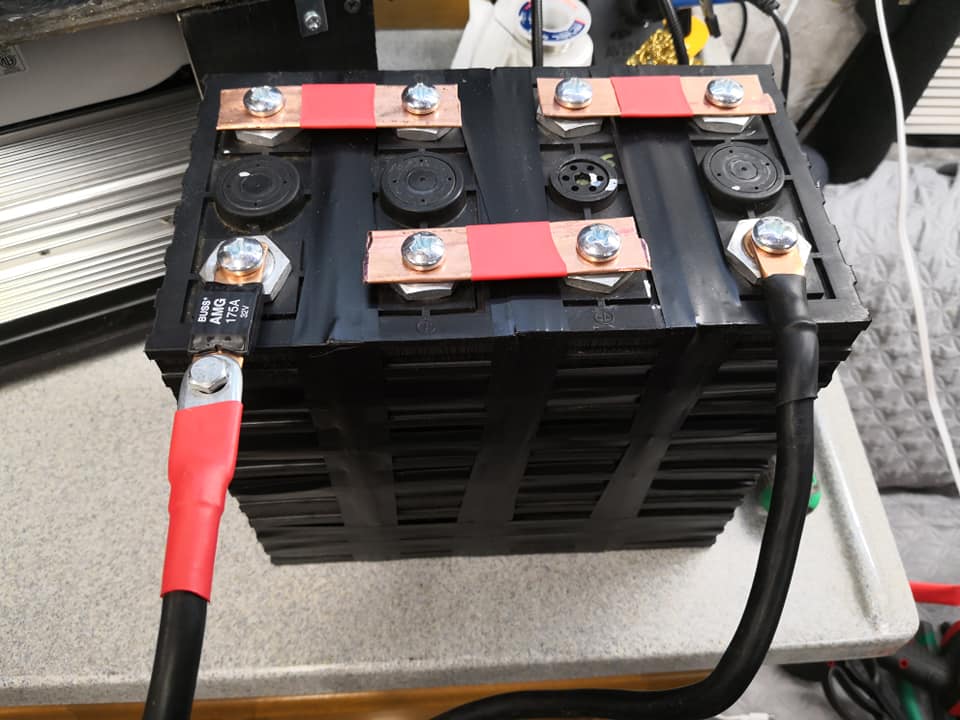 Four (4) 3.2V battery cells arranged in opposite polarities (negative to positive) for a compact series connection arrangement for a 12.8V battery cell group. 